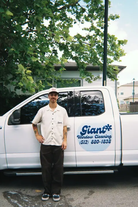 Keagen standing by the branded Giant Window Cleaning service truck in Austin