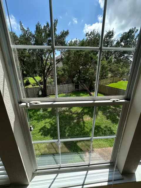 Bright view through a freshly cleaned upstairs window looking toward Austin trees