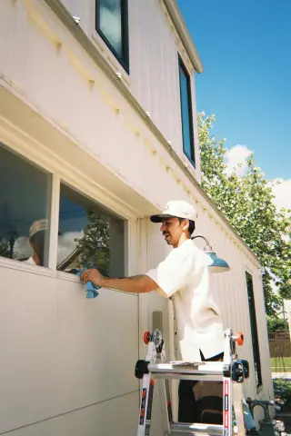 Crew member wiping a window on a bright Austin home exterior