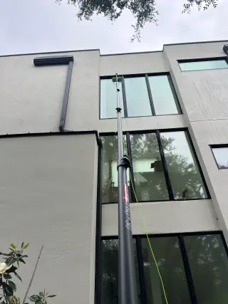 Water-fed pole cleaning high windows on a modern Austin property