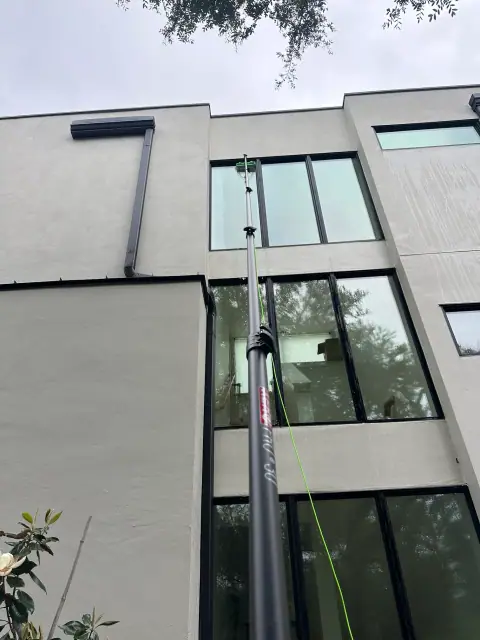 Water-fed pole cleaning high windows on a modern Austin property