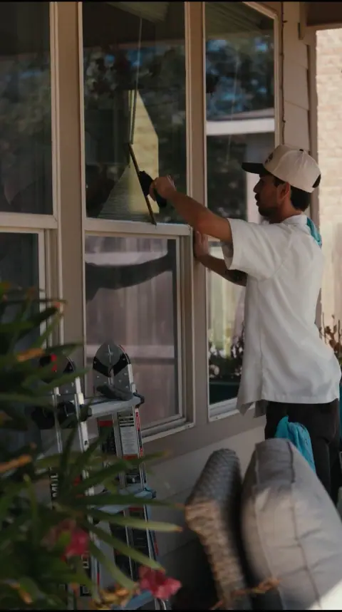 Giant Window Cleaning technician squeegeeing porch windows from outside