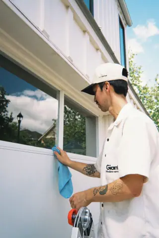 Giant Window Cleaning technician wiping a residential window sill with a blue towel