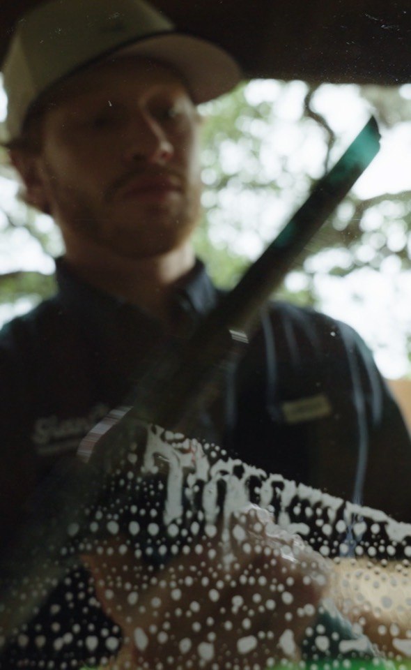 Giant Window Cleaning technician working through soapy glass on a residential window