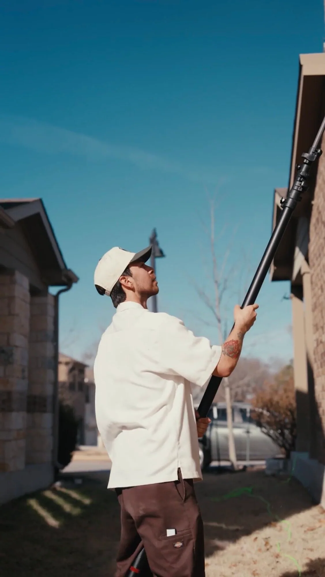 Crew member using an extension pole to clean upper exterior residential windows